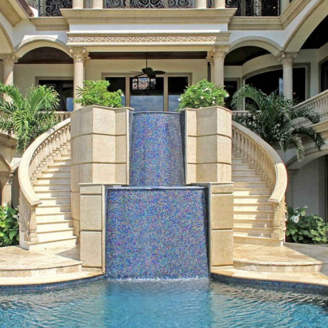 A beautiful outdoor fountain that flows into an in ground pool.