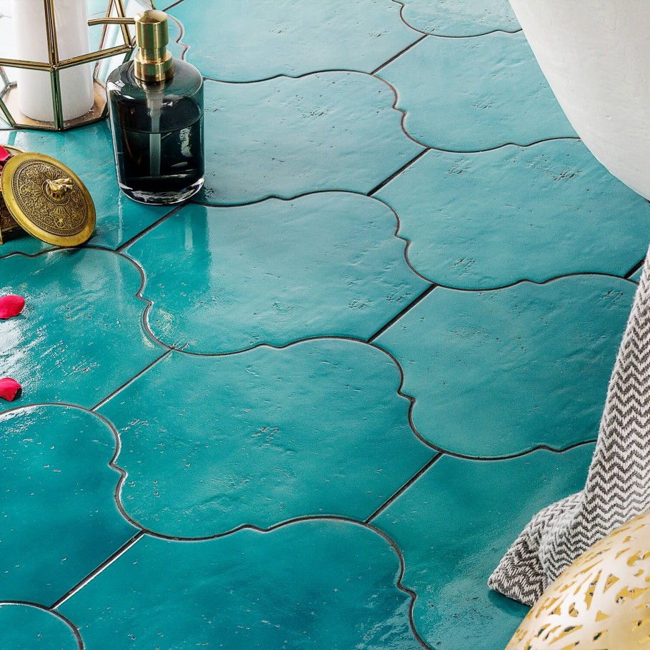 Aquamarine arabesque tile on the floor with antiqued soap pump and chevron towel 
