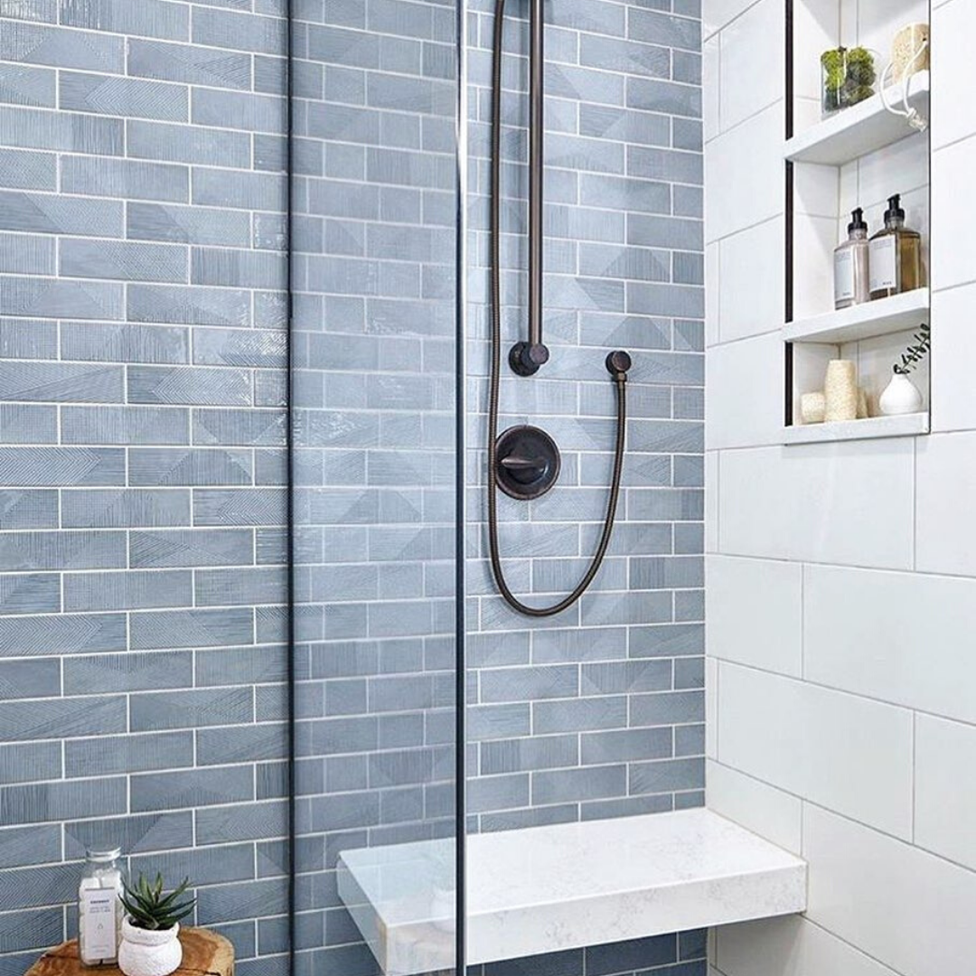 A modern walk in shower with glass panel using Enigma Ash Blue 2x8 Polished Ceramic Wall Tile 