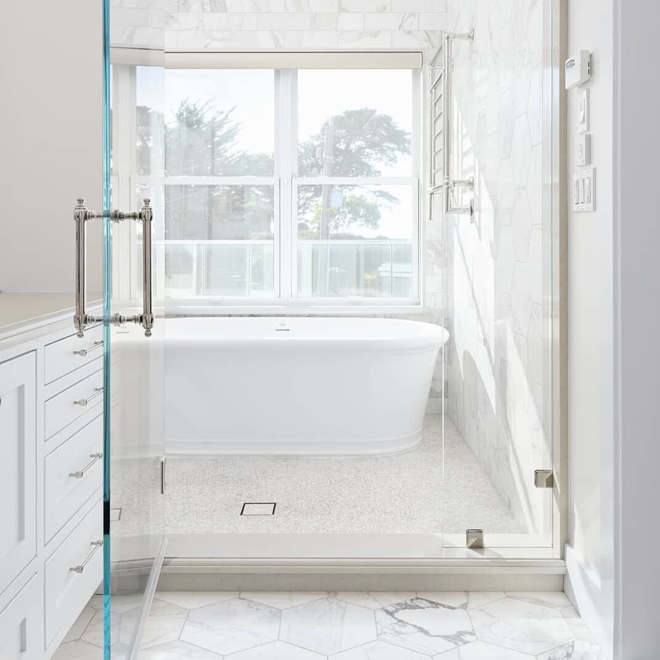 Calacatta 4x8 Polished Marble Tile shown with the Mother of Pearl Oyster White Tile in a bright bathroom. 